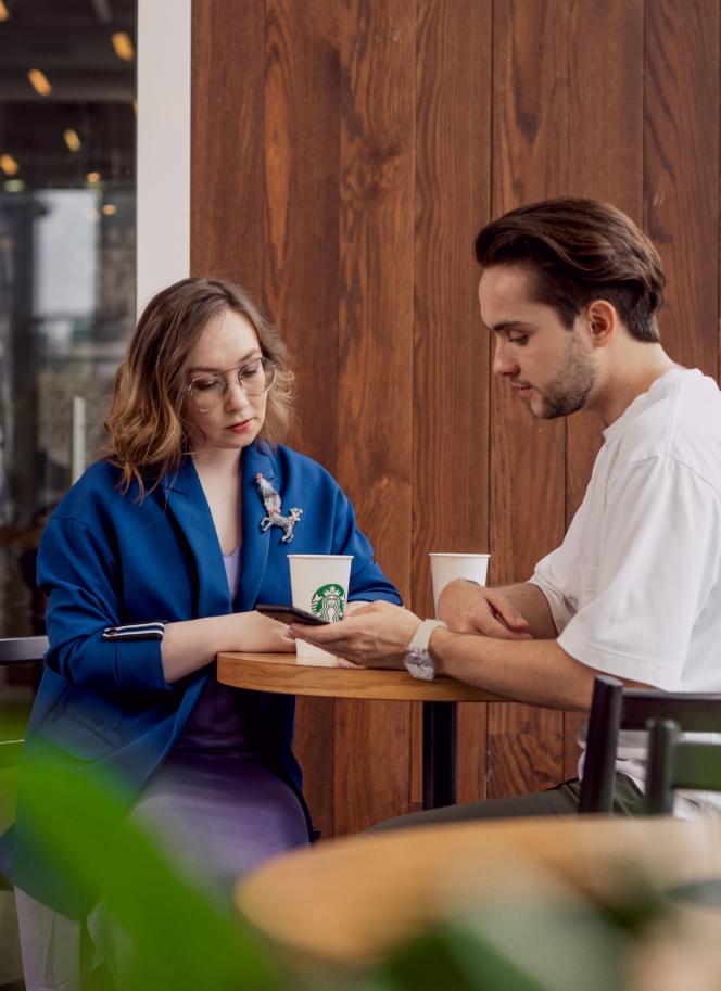 Мужчина и женщина сидят в кафе и смотрят в телефоны